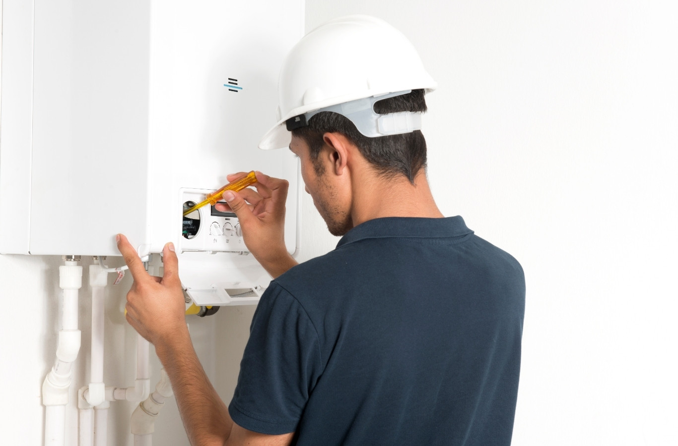 Technician in a hard hat adjusting wall boiler controls, a step in Climate Systems boiler maintenance in McCandless, PA